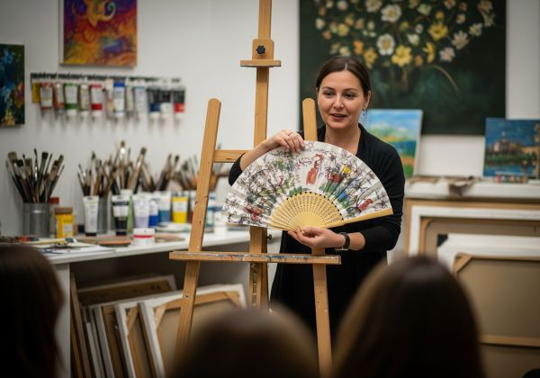 Frau präsentiert kreatives Kunstwerk vor einer kleinen Gruppe in einem Atelier
